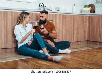 Shot Of An Affectionate Couple Drinking Wine While Sitting On A Kitchen Floor