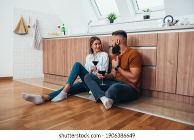 Shot Of An Affectionate Couple Drinking Wine While Sitting On A Kitchen Floor