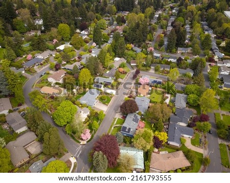 Shot from the air. Small green city, suburb. Roofs of cozy houses, many trees, bushes, green lawns. Comfortable place to stay, environmentally friendly place. Map, topography, construction.