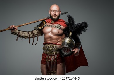 Shot Of Antique Roman Warrior With Muscular Build Holding Helmet And Spear.