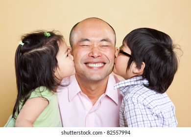 A Shot Of An Asian Father Kissed By His Kids