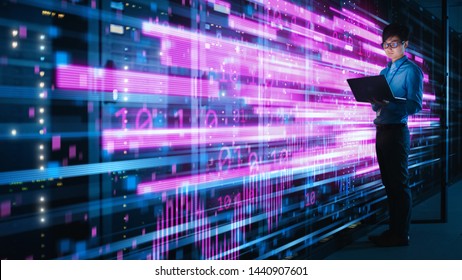 Shot Of Asian IT Specialist Using Laptop In Data Center Full Of Rack Servers. Concept Of High Speed Internet With Pink Neon Visualization Projection Of Binary Data Transfer