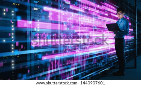Shot of Asian IT Specialist Using Laptop in Data Center Full of Rack Servers. Concept of High Speed Internet with Pink Neon Visualization Projection of Binary Data Transfer