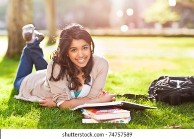 A shot of an asian student studying on campus lawn