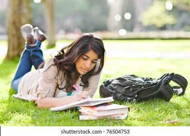 A shot of an asian student studying on campus lawn