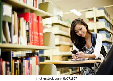 A Shot Of An Asian Student Texting On The Phone On Campus