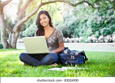 A shot of an Asian student working on laptop on campus