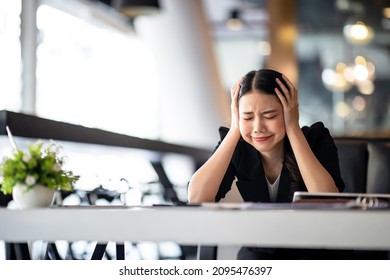 Shot of Asian young businesswoman looking stressed while sitting in her office in front of the laptop.