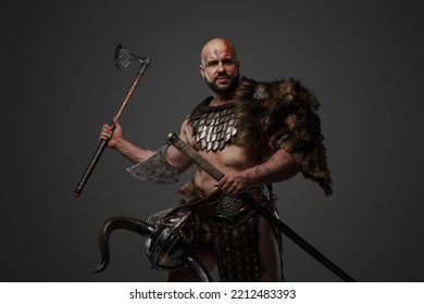 Shot Of Assaulting Viking With Muscular Build And Fur Holding Two Axes.