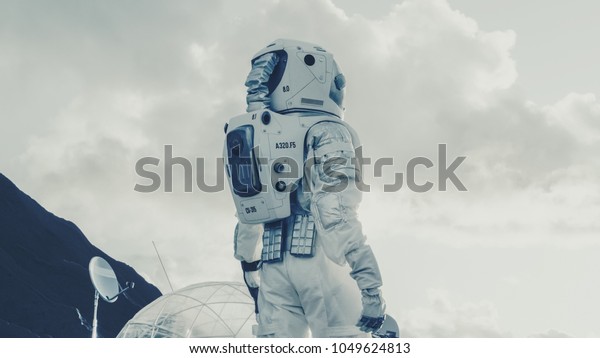Shot of the Astronaut\
Looking Around on Frozen Alien Planet. In the Background His Base/\
Research Station. Technological Advance Brings Space Exploration,\
Colonization.
