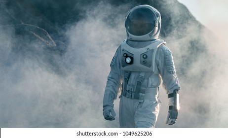 Shot of Astronaut Walking on Alien Rocky Planet that is Covered with Gas and Smoke. Humans Overcoming Difficulties. Scientific Progress. - Powered by Shutterstock