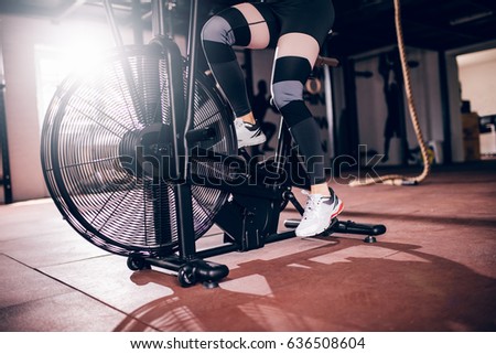Shot of athlete woman exercising on assault air bike.