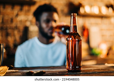 Shot of attractive african young happy smiling man drinking beer bottle in the bar close up portrait.