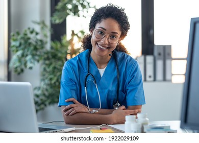 Shot Of Attractive Afro Female Doctor Smiling Looking At Camera While Working With Laptop In The Consultation.