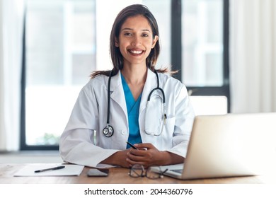 Shot Of Attractive Female Doctor Smiling Looking At Camera While Working With Laptop In The Consultation.