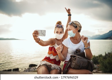 Shot Of Attractive Female Friends Wearing With Protective Mask And Making Selfie With Smartphone While Exploring The Wonderful City Of Mediterranean.