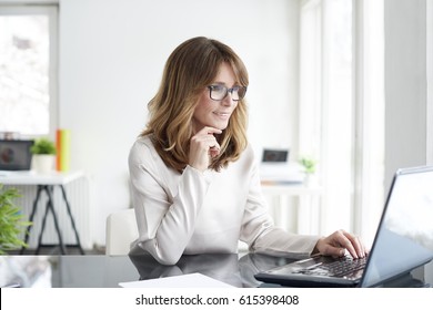 Shot of an attractive mature businesswoman working on laptop in her workstation. - Shutterstock ID 615398408