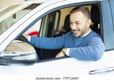 Shot of an attractive mature handsome bearded man smiling happily looking in the sidemirror sitting in the car at the dealership showroom copyspace confidence success happiness emotions