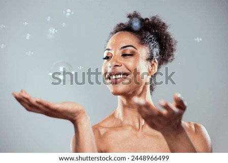 Shot of attractive mature woman playing with soap and water bubbles on isolated white