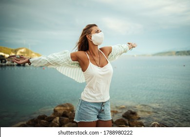 Shot of an attractive relaxed young woman with protective N95 mask enjoying a vacation on the beach during the COVID-19. - Powered by Shutterstock