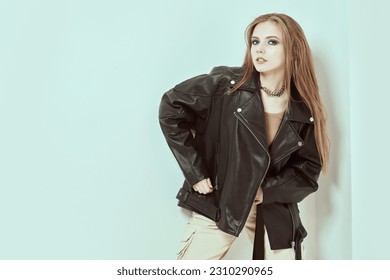 Shot of an attractive rock star teen girl posing on white studio background with copy space. Make-up with dark shiny smokey eyes, long combed hair. Modern youth pop and rock culture.