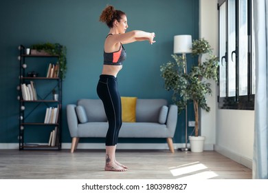 Shot of attractive sporty young woman doing hypopressive exercises in living room at home.