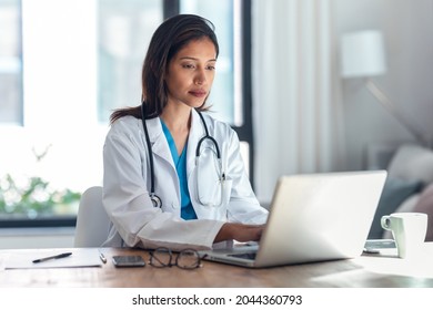 Shot of attractive young female doctor working with her computer in medical consultation. - Powered by Shutterstock