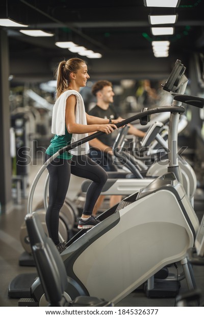 Shot of an attractive young woman exercising\
on the stepmill machines   at the\
gym.
