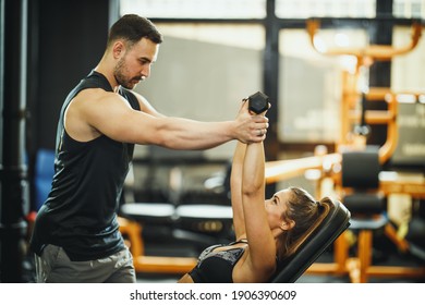 Shot of an attractive young woman working out with personal trainer at the gym.