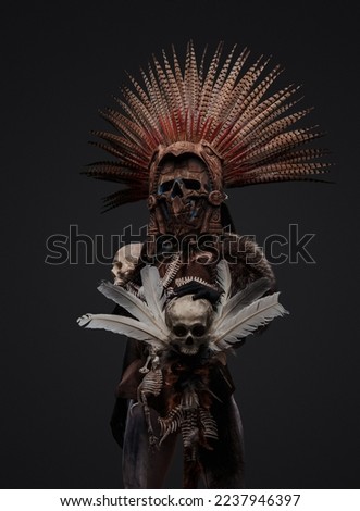 Shot of aztec witch dressed in ceremonial headdress holding staff with skull.