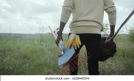 Shot back african american young man walk plant tree on field garden forest volunteering charity ecology seedling agriculture care environment spring leisure natural organic plantation slow motion - Powered by Shutterstock