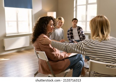 shot back view of therapist and group of multi-age patients putting hands on each others shoulders sitting in circle during group therapy session as symbol of support - Powered by Shutterstock