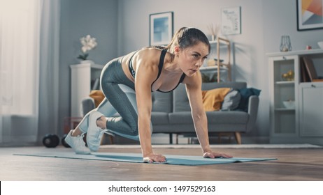 Shot of a Beautiful Confident Strong Fitness Female in a Grey Athletic Outfit is Doing Mountain Climber Exercises in Her Bright and Spacious Apartment with Cozy Minimalistic Interior.