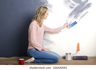 Shot Of A Beautiful Mature Woman Matching Color While Painting Wall In Her Living Room.