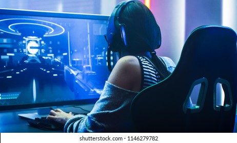 Shot of the Beautiful Pro Gamer Girl Playing in First-Person Shooter Online Video Game on Her Personal Computer. Casual Cute Geek wearing Glasses and Headset. Neon Room. eSport Cyber Games Internet - Shutterstock ID 1146279782