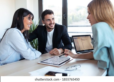 Shot of beautiful real-estate agent showing house plans on electronic tablet while talking to the couple about buying the house in the office. - Powered by Shutterstock