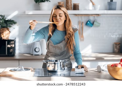 Shot of beautiful woman cooking healthy food in casserole while blowing the spoon to taste the food in the kitchen at home. - Powered by Shutterstock