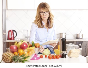 Shot of a beautiful woman writing recipe into her recipe book while cooking in her kitchen.