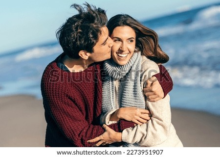 Shot of beautiful young couple in love enjoying the day in a cold winter on the beach.