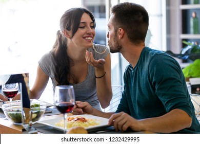 Shot of beautiful young couple sharing single spaghetti getting closer to kissing in the kitchen at home.