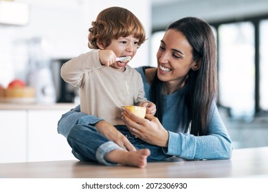 Shot of beautiful young mother giving food to her son while having fun in the kitchen at home. - Powered by Shutterstock