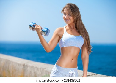 Shot Of A Beautiful Young Woman Lifting Weights Outside