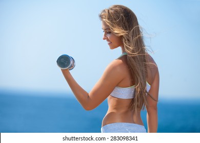 Shot Of A Beautiful Young Woman Lifting Weights Outside