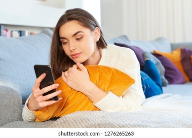 Shot of beautiful young woman lying on sofa and text messaging while relaxing at home.  - Shutterstock ID 1276265263