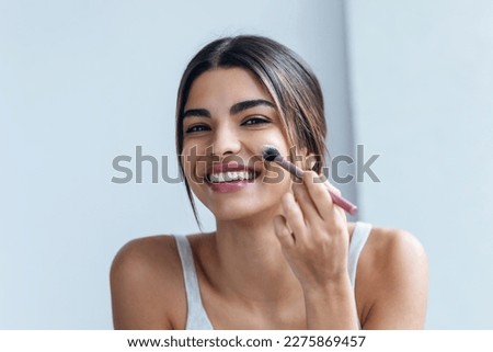 Shot of beautiful young woman making make-up near mirror in the bathroom. Foto stock © 