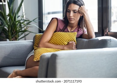 Shot Of Beautiful Young Woman Thinking And Worried Sitting On Couch At Home.