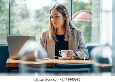 Shot of beautiful young woman working with her laptop while having breakfast in a coffee shop - Powered by Shutterstock