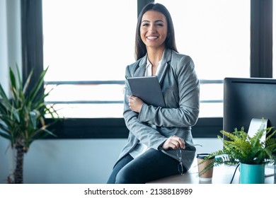 Shot of beauty business woman using her digital tablet while sitting on a desk in a modern startup office.