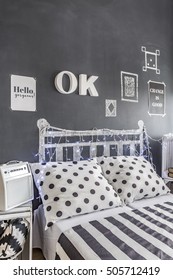 Shot Of A Bed Standing Against A Chalkboard Wall In A Small Bedroom