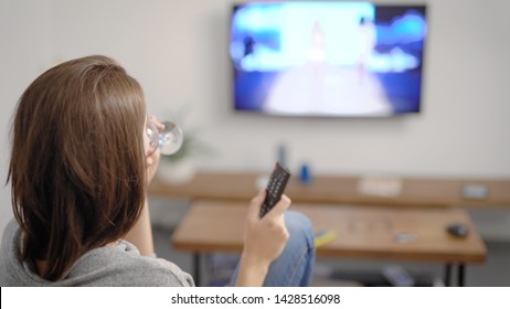 Shot From Behind Of A Lovely Girl Sitting In Couch And Watching TV, Relaxing Time.